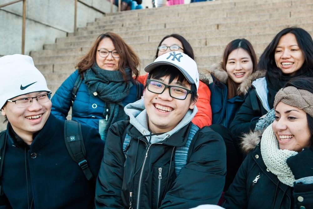 7 internationals students smiling and sitting on outdoor staircase