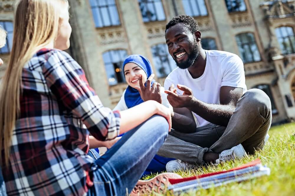 three diverse friends sit outside chatting