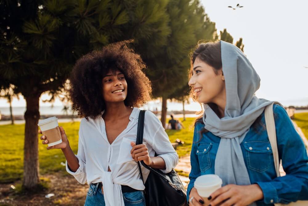 Muslim woman walks with african american woman in park