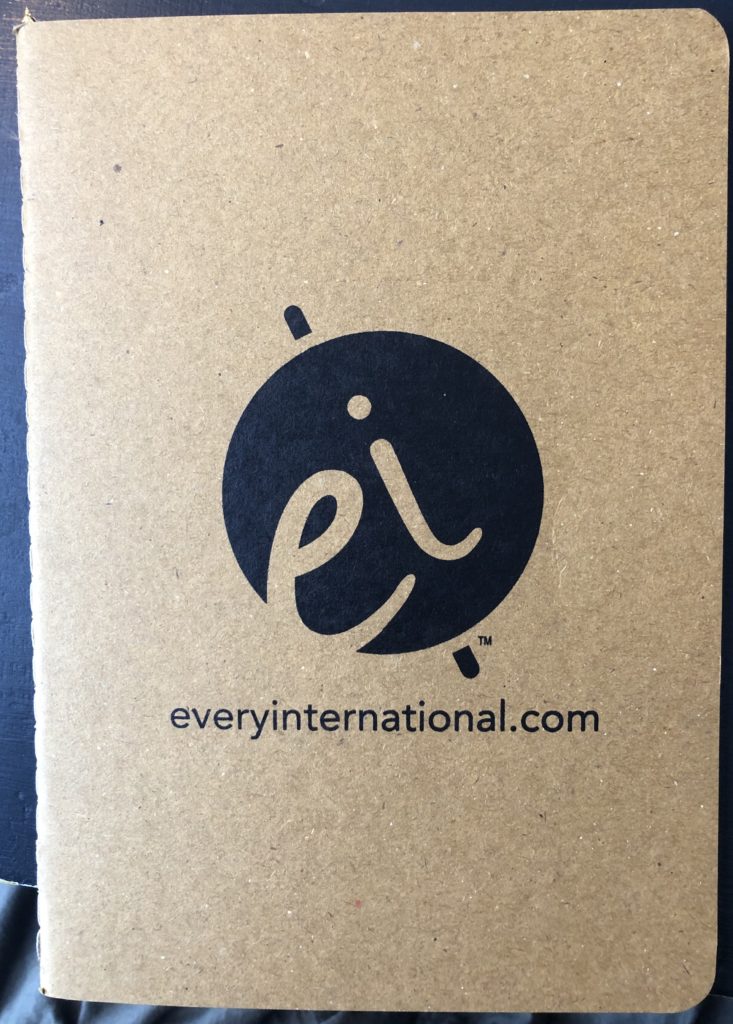 small brown notebook made of recycled paper with EveryInternational.com and logo printed on it