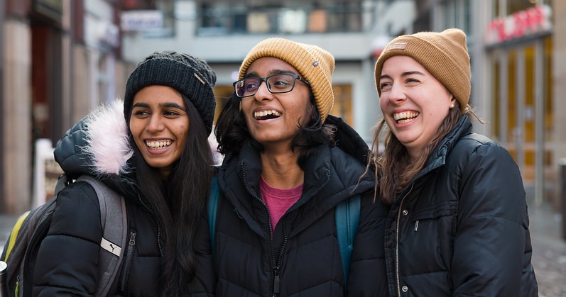 two south asian college students pose with an American student outside in the cold