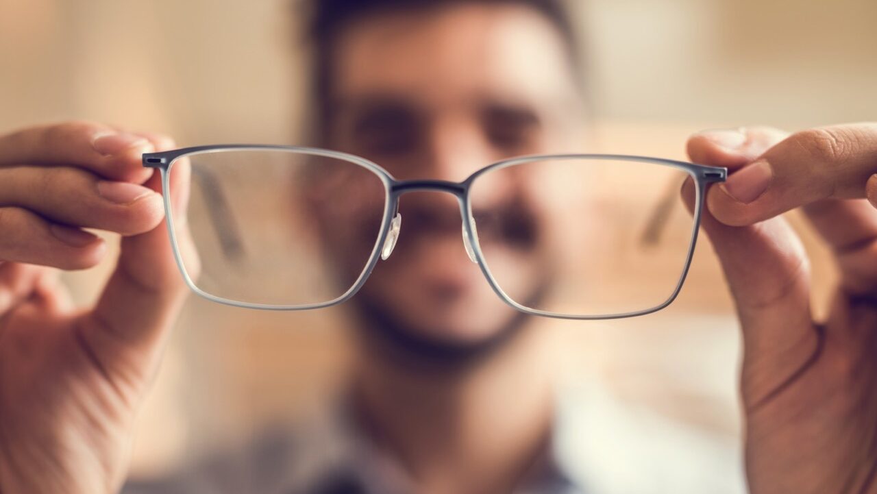 closeup of man holding up eyeglasses before putting them on