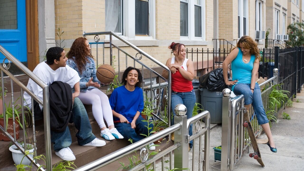 diverse group of young adults hang out on a porch