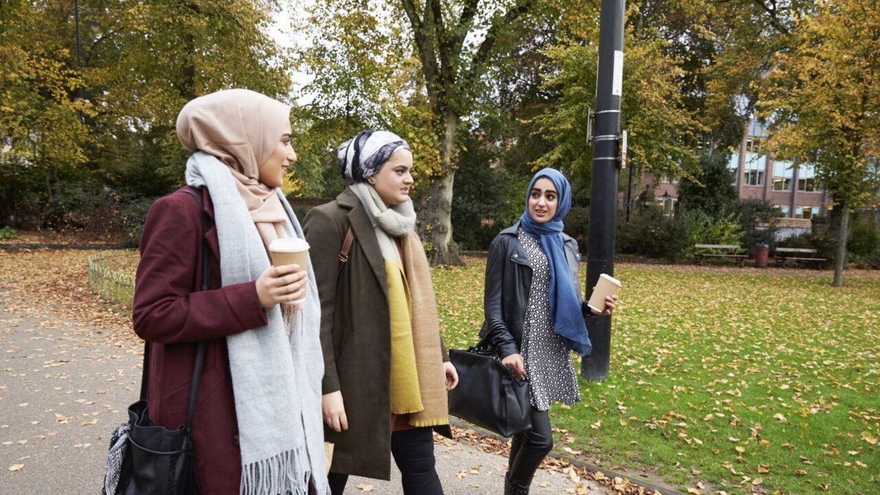 3 muslim women walk outside drinking coffee