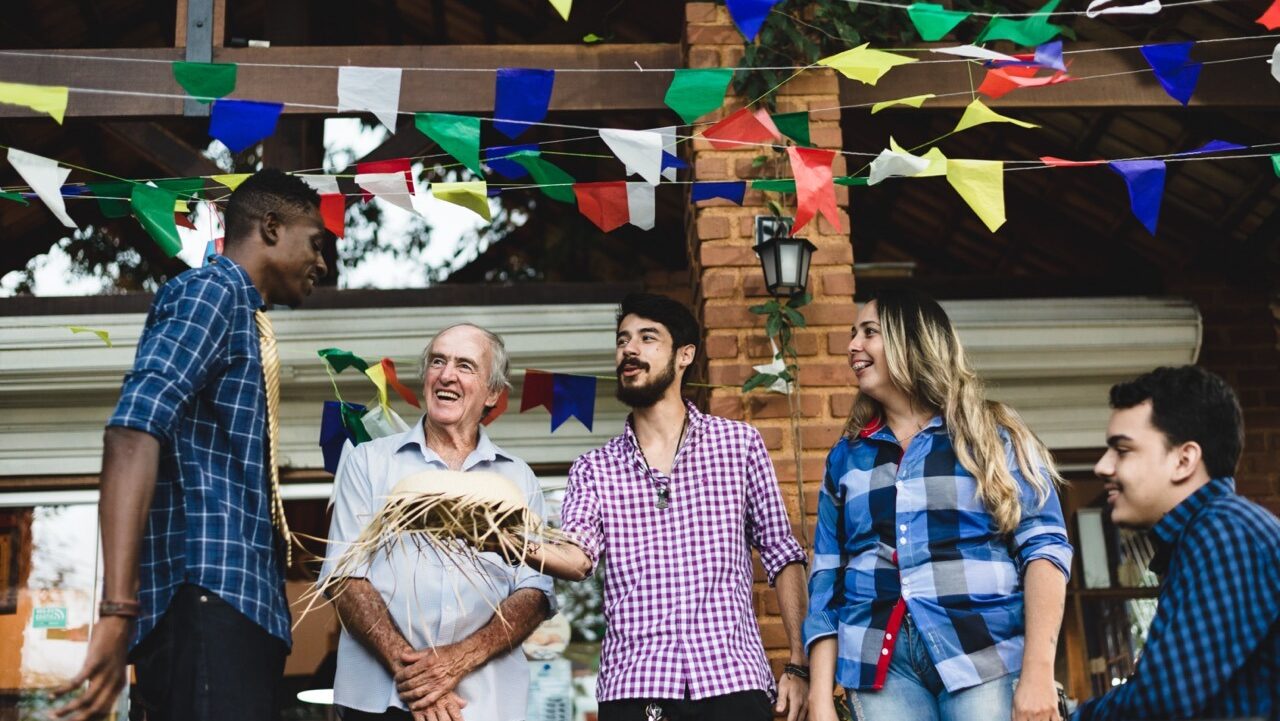 an older man chats with a group of diverse international students outside at a party