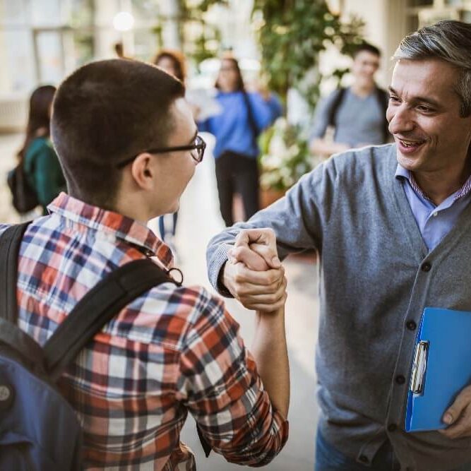 American man and international student clasp hands in greeting