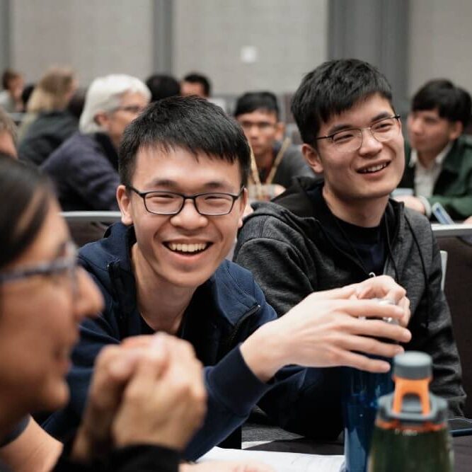 two male Chinese students smile at a conference table